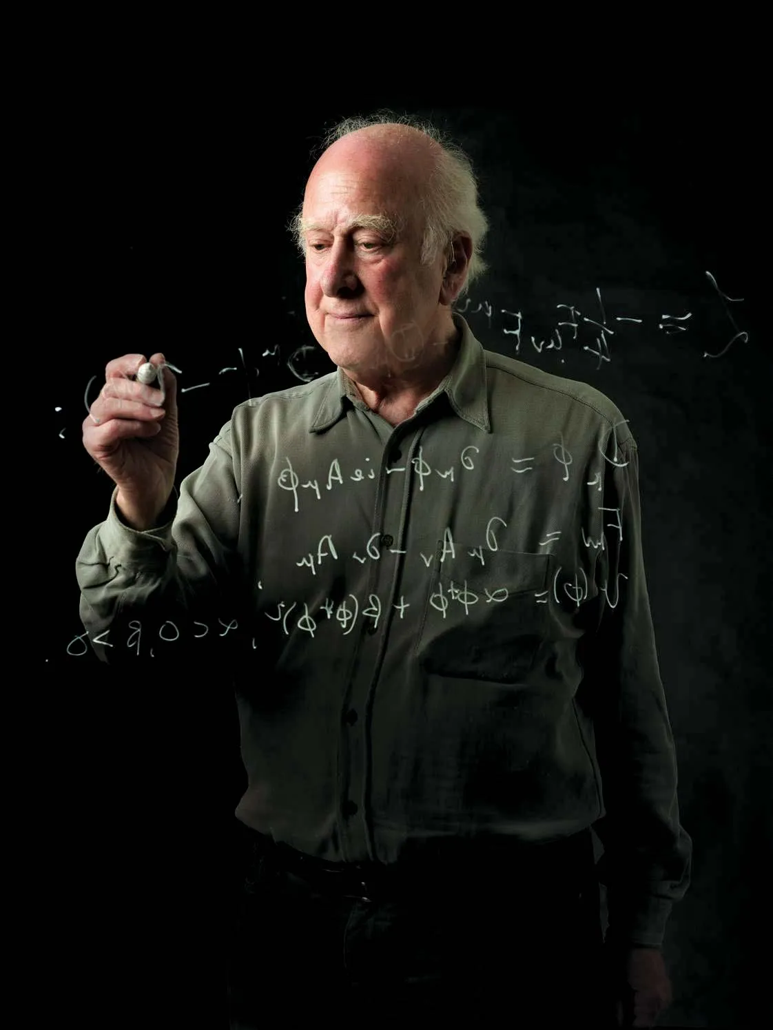 Peter Higgs writing equations on a whiteboard